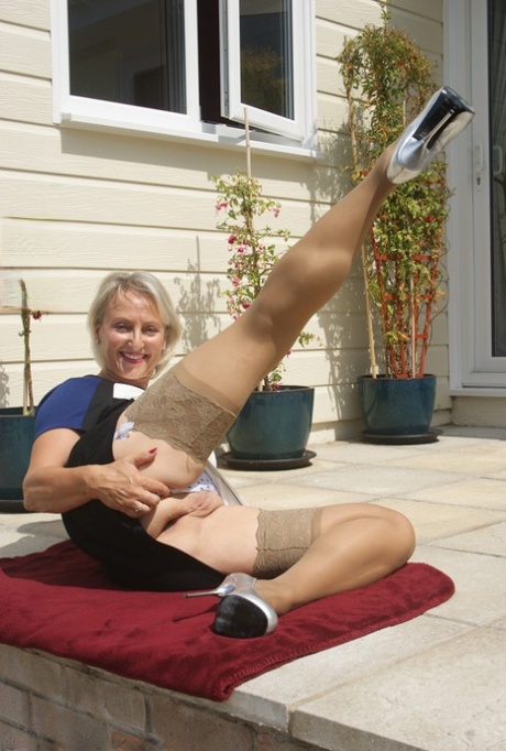 Leggy mature dame in stockings exposing big breasts outdoors in high heels