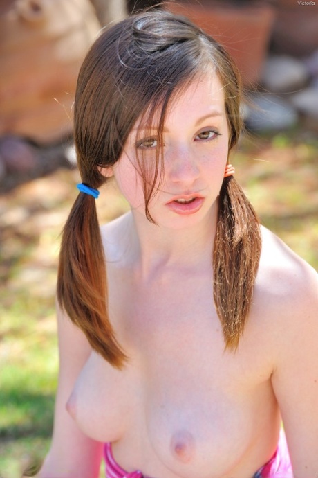 Young adult with pigtails Victoria reveals her nice breasts & plays with a water hose