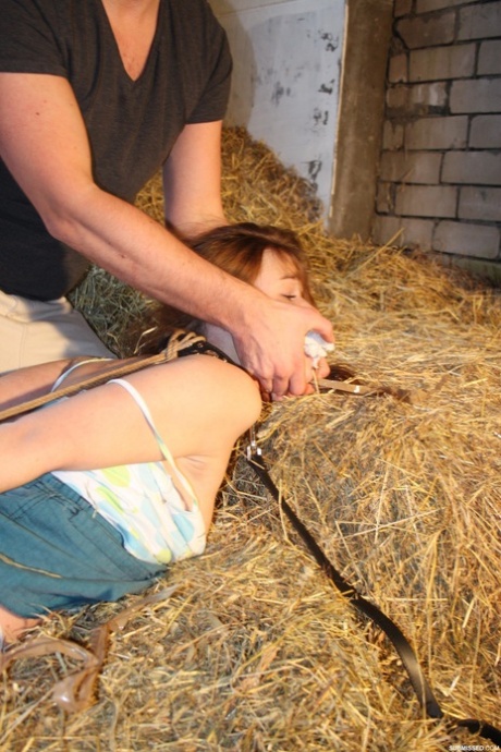 Naughty pantiless young adult Anouk bound with rope & gagged with tape in the barn