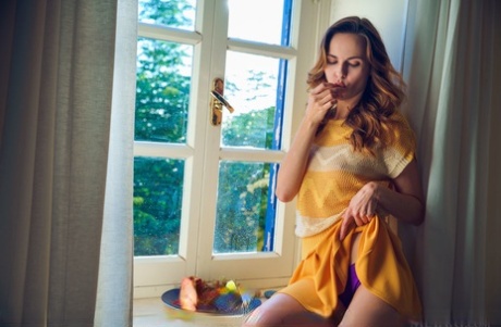 Nice young adult Nasita undresses on her bed for artistic poses on a window sill