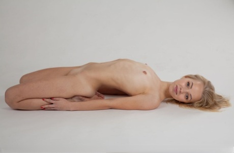 Slim blonde young adult with tiny breasts Estel K removes panties to model totally natural