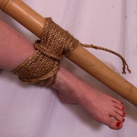 Busty blonde is tied natural and spread eagle style to a bamboo frame