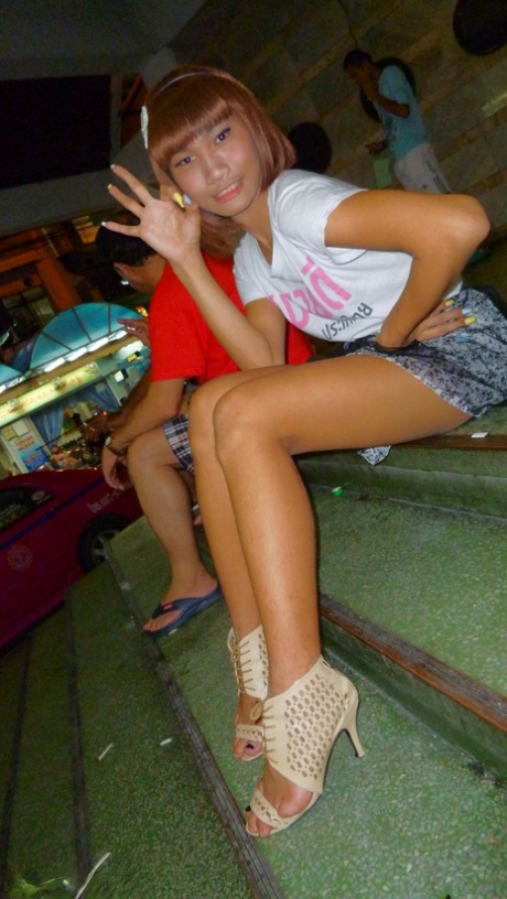 Red-haired Asian ladyboy lifts dress up to flash manhood in public place