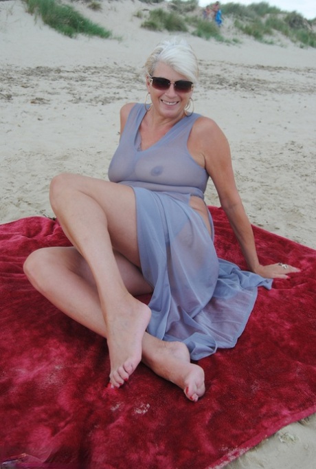 Beautiful busty mature Dimonty poses fully clothed in sheer dress at the beach