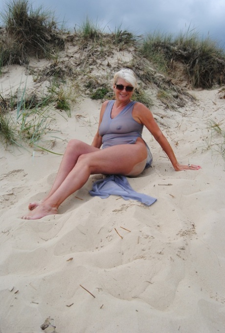 Beautiful busty mature Dimonty poses fully clothed in sheer dress at the beach