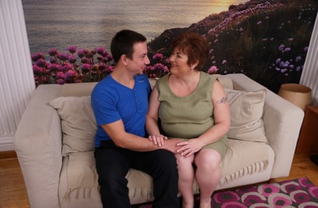 Alluring mature BBW bares her great big breasts for her young boy toy to suck on