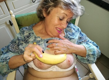 Horny granny Caro sticks a banana inside her natural femininity on kitchen chair