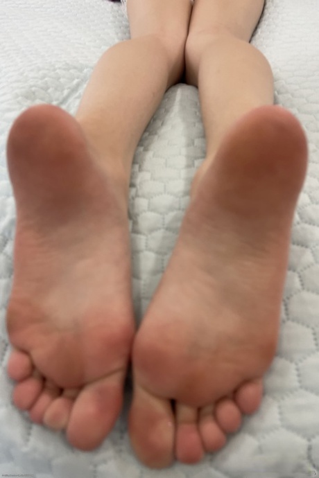Skinny young adult displaying her pretty feet and holes up close in a solo