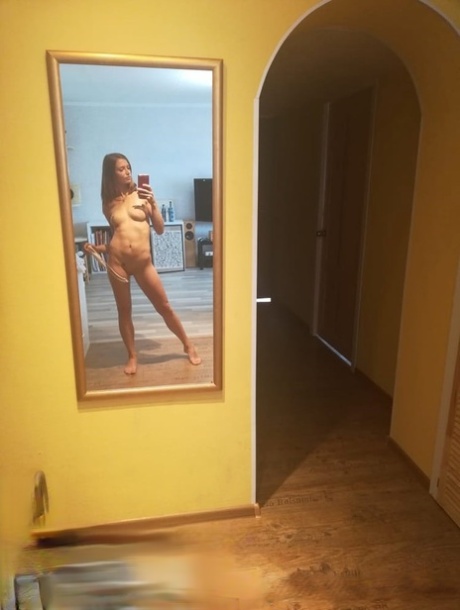 Slender authentic young adult takes selfies while posing natural in the mirror