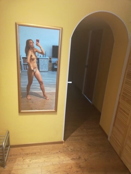 Slender authentic young adult takes selfies while posing natural in the mirror