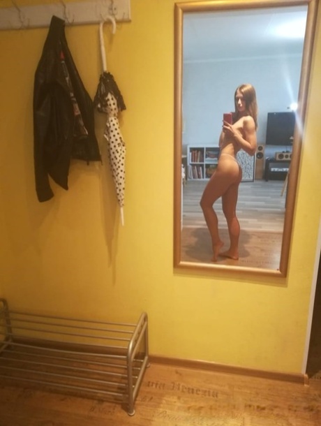 Slender authentic young adult takes selfies while posing natural in the mirror