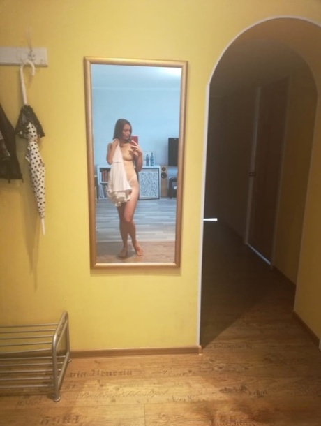 Slender authentic young adult takes selfies while posing natural in the mirror