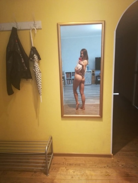 Slender authentic young adult takes selfies while posing natural in the mirror