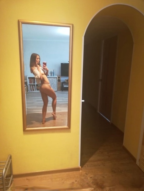 Slender authentic young adult takes selfies while posing natural in the mirror