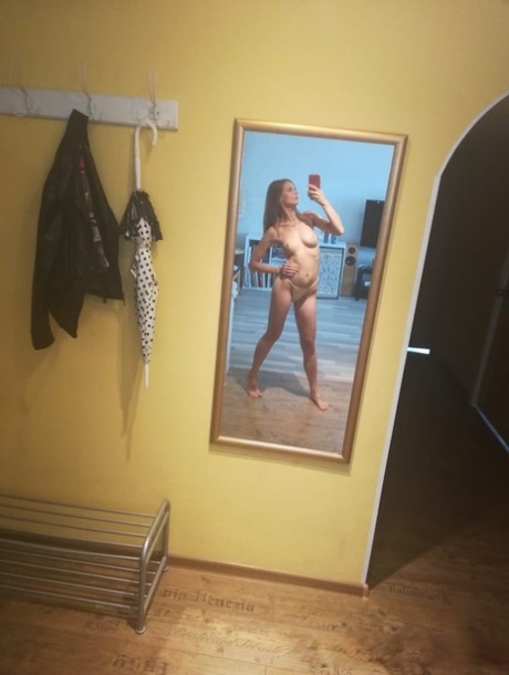 Slender authentic young adult takes selfies while posing natural in the mirror