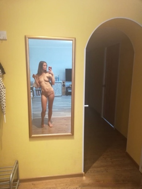 Slender authentic young adult takes selfies while posing natural in the mirror