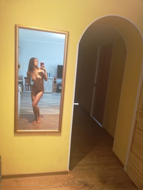 Slender authentic young adult takes selfies while posing natural in the mirror