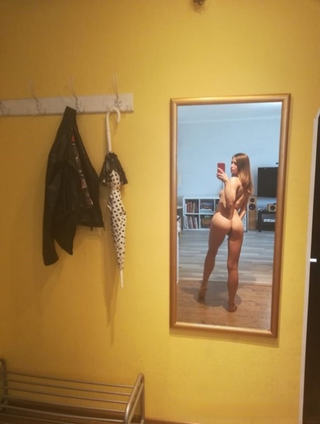 Slender authentic young adult takes selfies while posing natural in the mirror