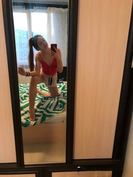 Amateur honey with small tits posing naked in front of a mirror