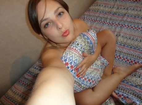 Amateur honey with blue eyes takes hot selfies while stripping on a bed