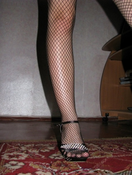 Brunette amateur posing in her fishnet pantyhose and high heels in a solo