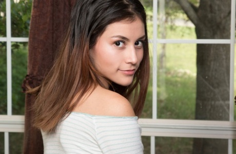 Young brunette Amelia Pearl holds her face firm while petting her bald femininity